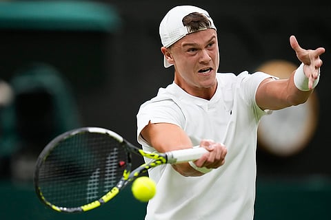 Holger Rune plays a forehand return to Novak Djokovic